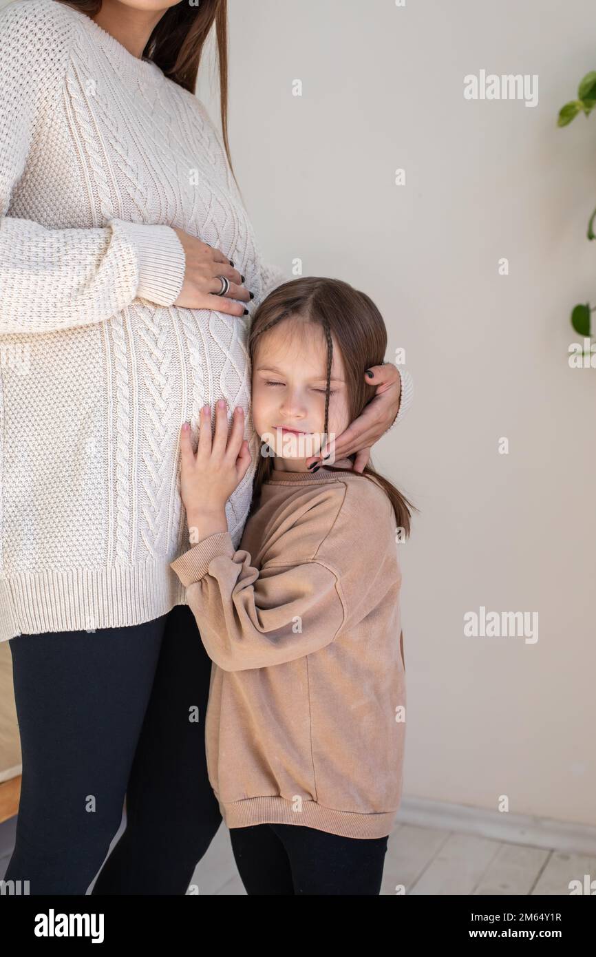 Süßes kleines Mädchen, das die Bewegungen des Babys im Bauch schwangerer Mütter hört