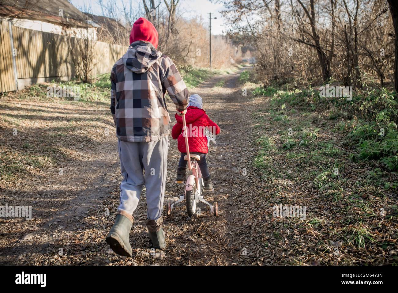 Der Bruder nimmt seine Schwester mit auf ein Fahrrad. Ukrainischer Kindereinwanderer auf einer Spende eines gebrauchten Fahrrads durch eine Gastfamilie. Stockfoto