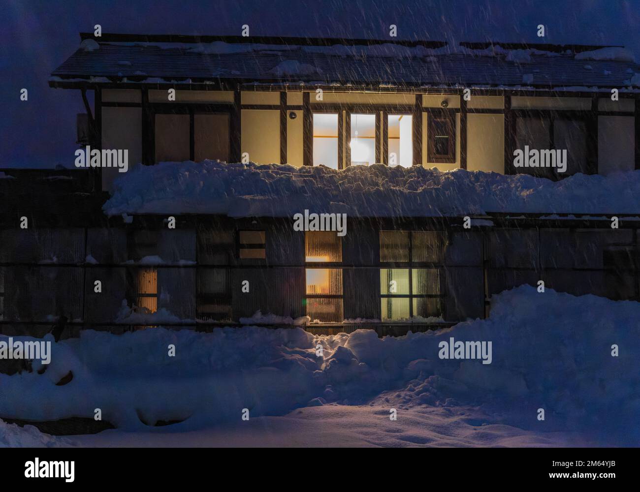 Vor dem traditionellen japanischen Gasthaus fällt bei Nacht starker Schnee Stockfoto