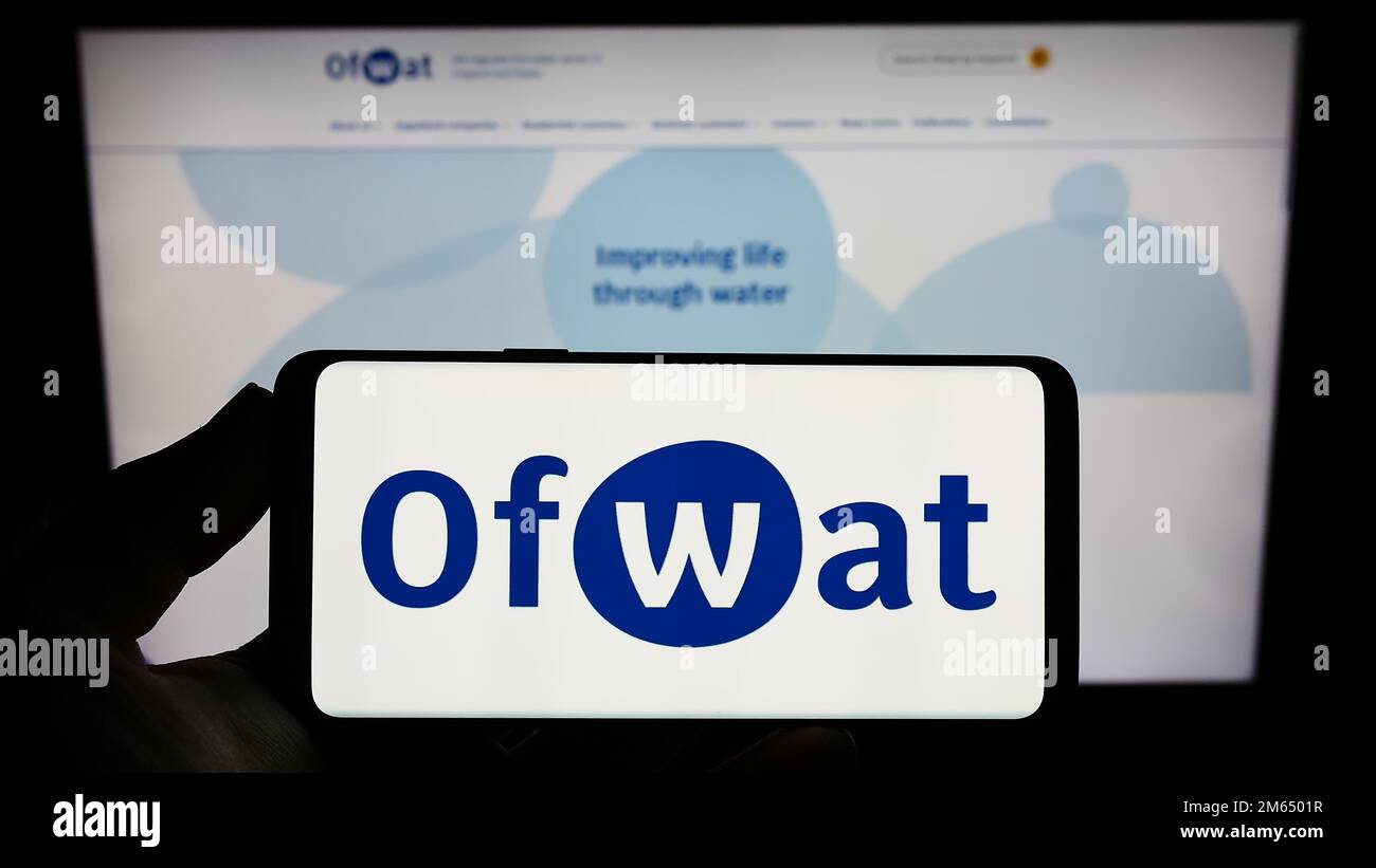 Person, die ein Smartphone mit dem Logo der Wasserdienstaufsichtsbehörde (Water Services Regulation Authority, Ofwat) auf dem Bildschirm vor der Website hält. Konzentrieren Sie sich auf das Display des Telefons. Stockfoto