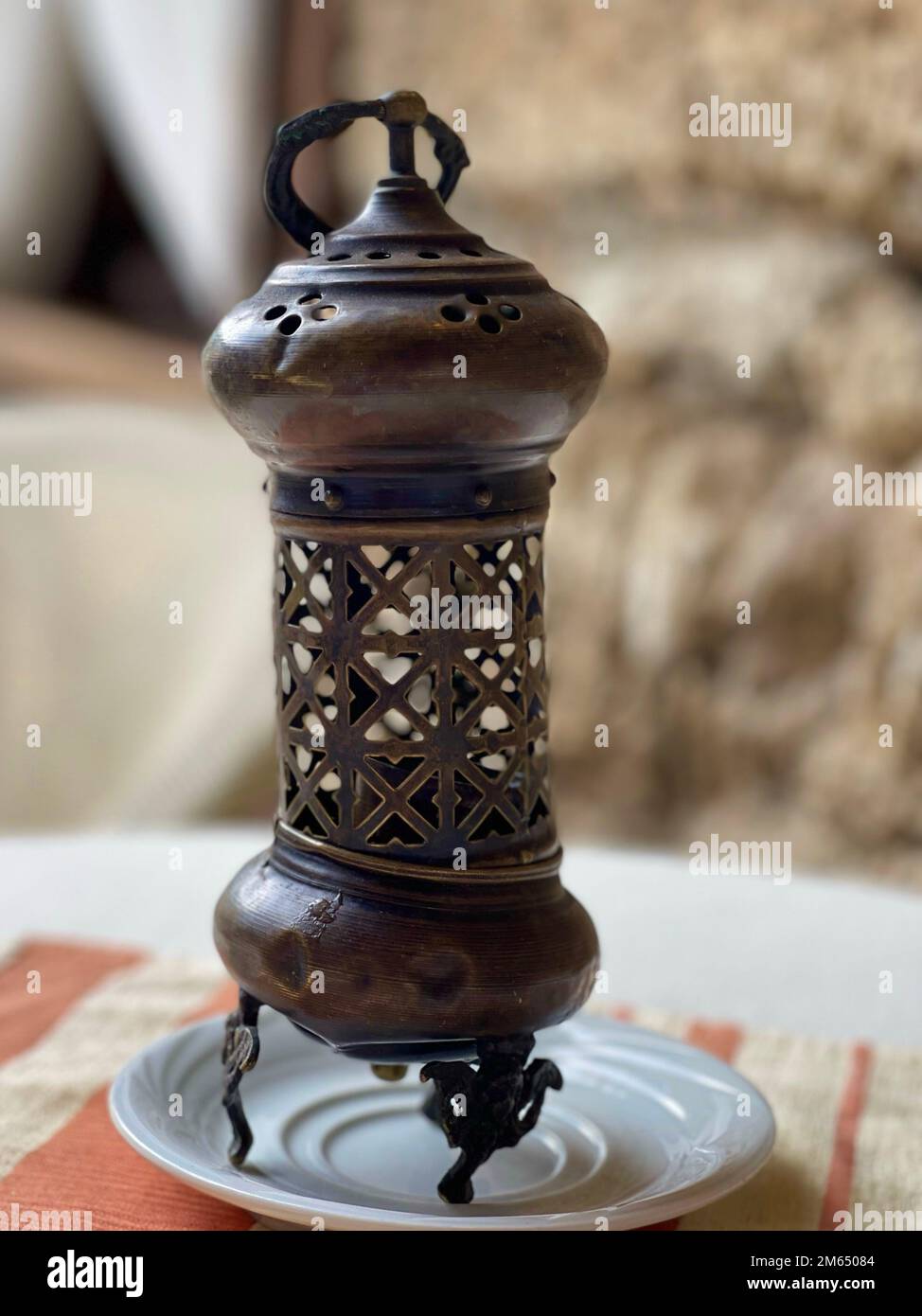 Kunstvoll verzierter orientalischer Kerzenhalter aus Metall auf einer Untertasse. Bronze. Messing. Muslimische Einrichtung. Stockfoto
