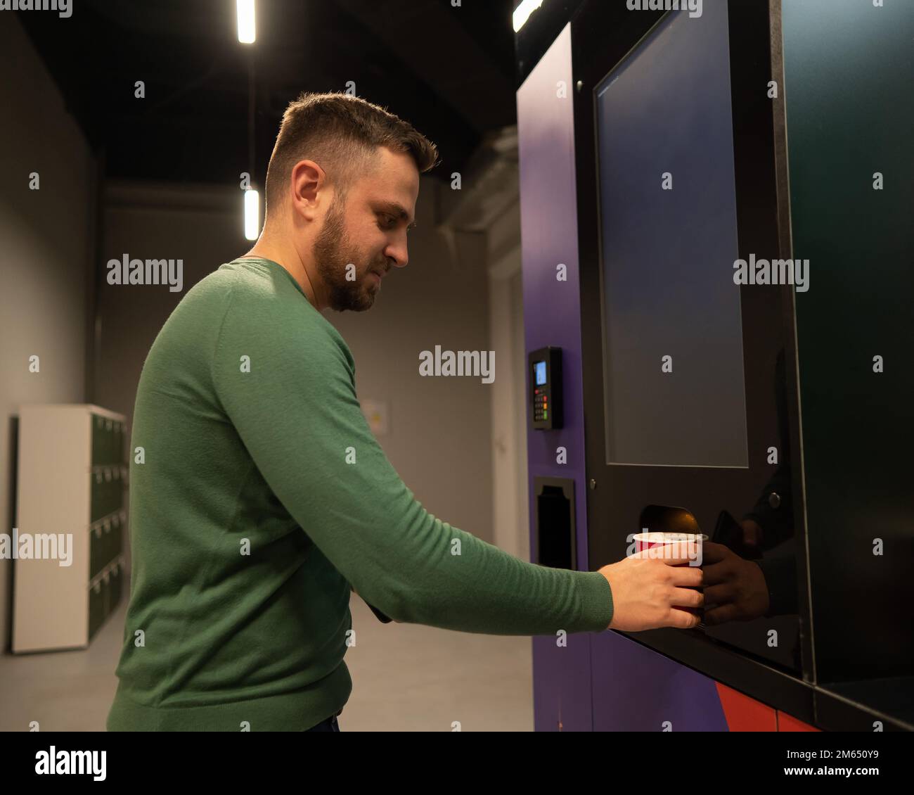 Ein weißer Mann gießt sich Kaffee aus einem Automaten ein. Stockfoto
