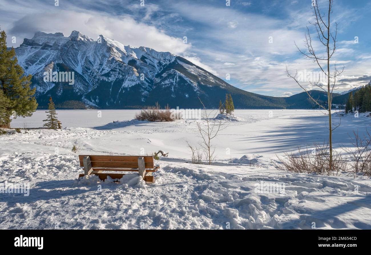 Winterparkbank am Frozen Lake Minnewanka im Banff National Park, Alberta, Kanada Stockfoto