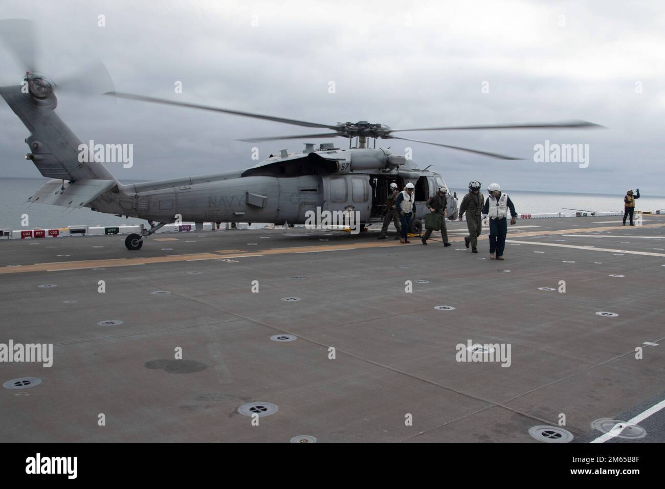 220403-N-XN177-5036 PAZIFIK (3. April 2022) – Hinten. ADM. Wayne Baze, Center, Commander, Expeditionary Strike Group 3, verlässt einen MH-60s Sea Hawk am Helicopter Sea Combat (HSC) 23 an Bord des Amphibienschiffs USS Tripoli (LHA 7), April 3. HSC-23 transportierte Baze nach Tripolis, um die USA zu beobachten Demonstration des Lightning-Trägerkonzepts des Marine Corps. Die Demonstration des Lightning-Trägerkonzepts zeigt, dass Tripolis und andere amphibische Angriffsschiffe bei Bedarf als spezielle Startrampen eingesetzt werden können, die kurze Starts/vertikale Starts der fünften Generation ermöglichen Stockfoto