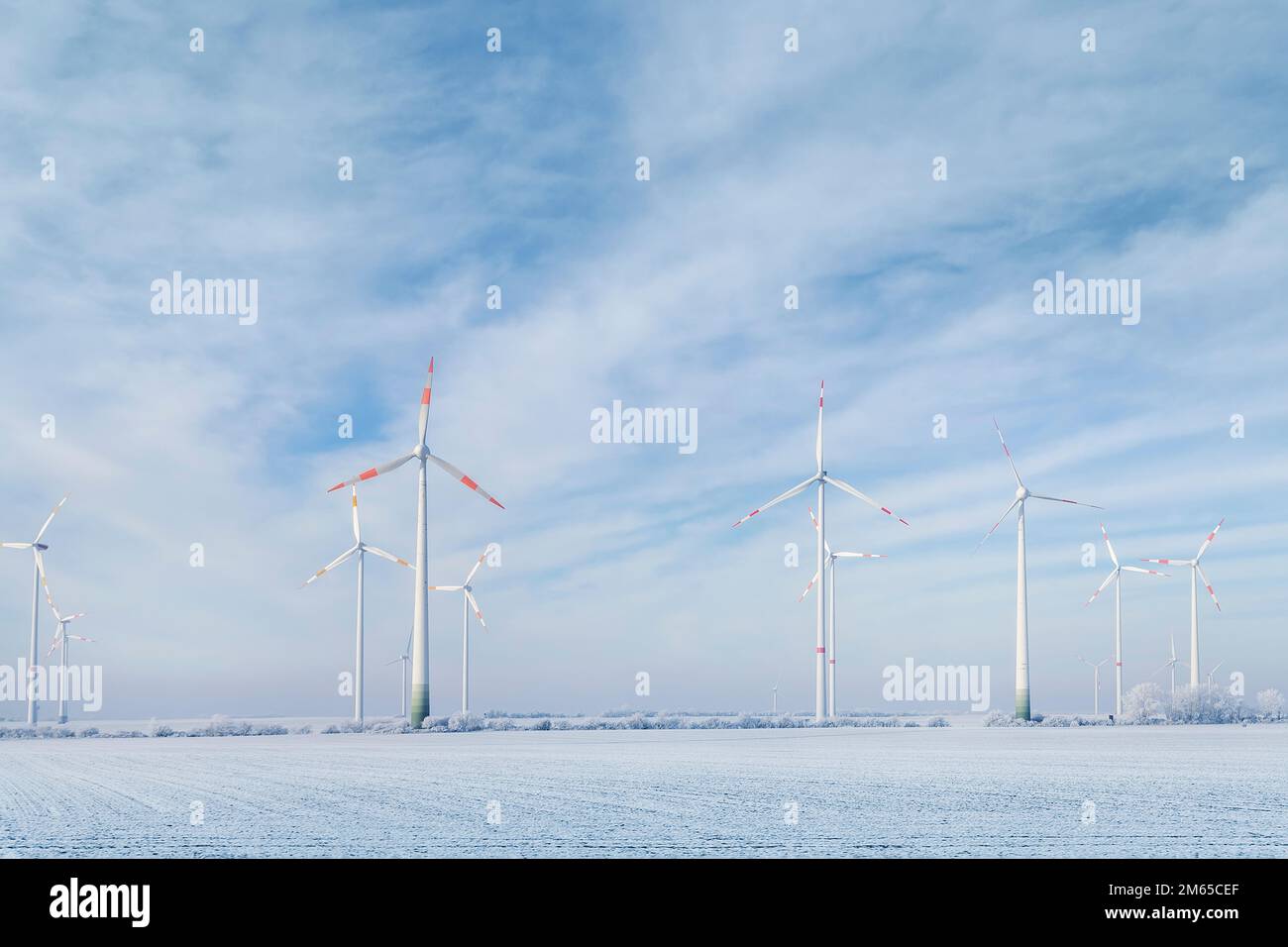 Malerischer Landschaftsblick auf weißes, verschneites, frostiges Feld und große, moderne Windturbinenmühle vor dem wunderschönen blauen Himmel. Ganzjährig sauberes Grün Stockfoto