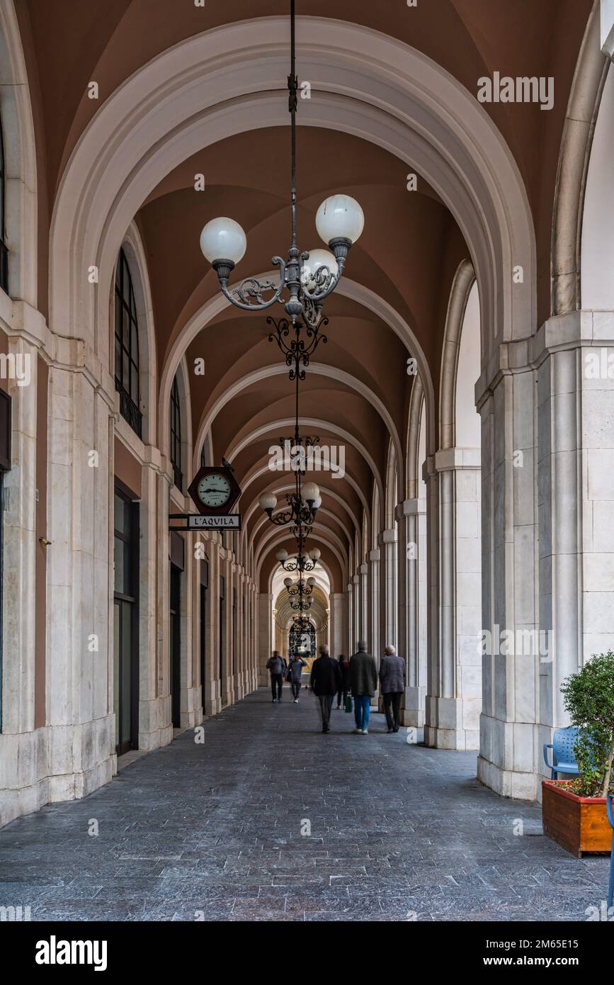 Die monumentalen Säulengänge, gestützt von Säulen, die in glatte Asche umhüllt und nach dem Erdbeben restauriert wurden, entlang des Corso Vittorio Emanuele in L'Aquila. Stockfoto