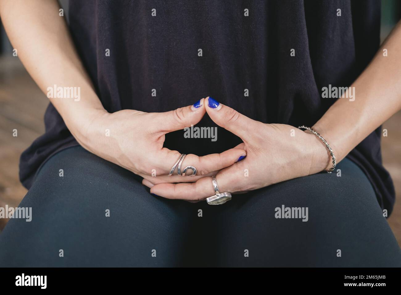 Nahaufnahme der Hände einer Jogi, die in Kniehaltung meditiert (vajrasana), während sie allein beim Vinyasa-Flow-Yoga-Training Sportbekleidung trägt Stockfoto