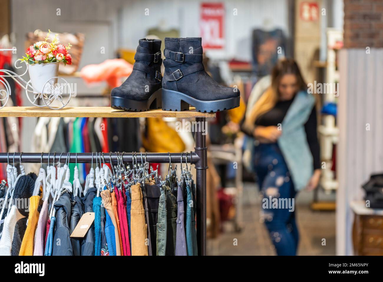 Übergewichtige Frau probiert Kleidung in einem Kleiderladen in der Übergröße-Abteilung an Stockfoto