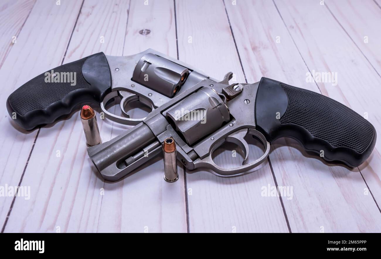 Zwei rostfreie Revolver aus Edelstahl, 357 Magnum und ein 44 Spezial mit einem Hohlkugeln für jeden zusammen auf weißem Holzhintergrund Stockfoto