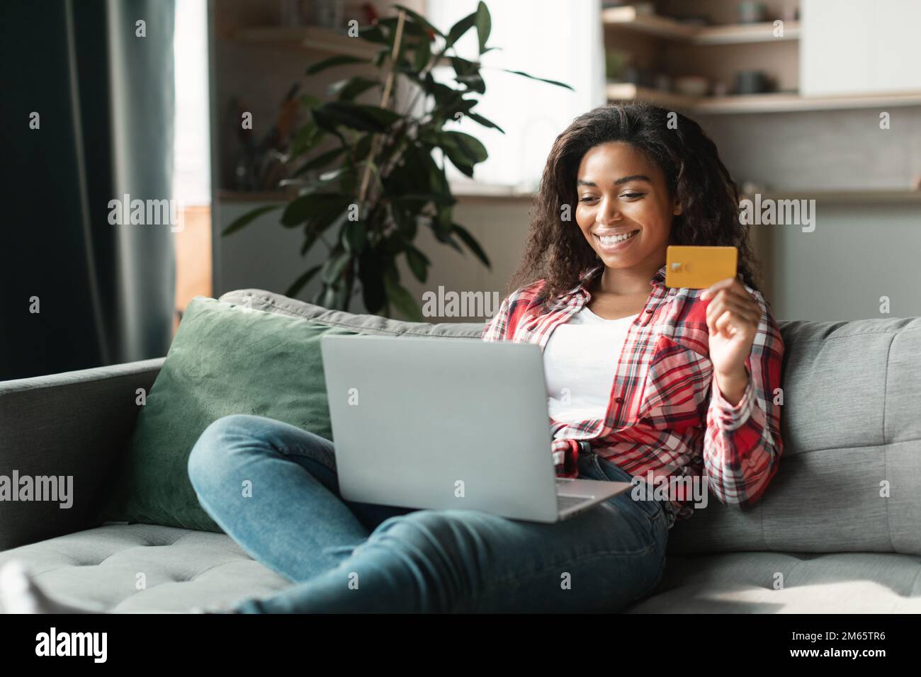 Online-Shopping, großer Verkauf. Lächelnde schwarze Millenial Lady Shopaholic benutzt Computer und Kreditkarte, um das Konto zu prüfen Stockfoto