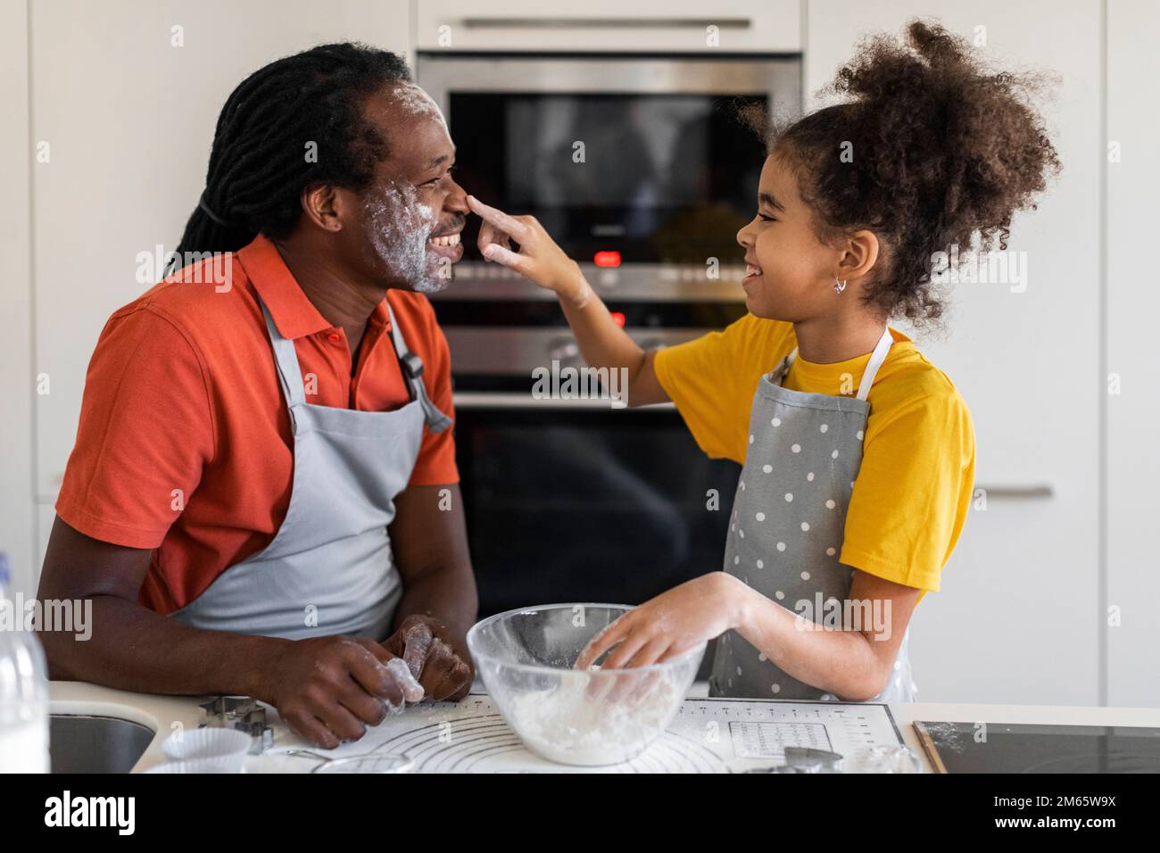 Fröhlicher Schwarzer Vater Und Tochter, Die Mit Floor Spielen, Während Sie In Der Küche Backen Stockfoto