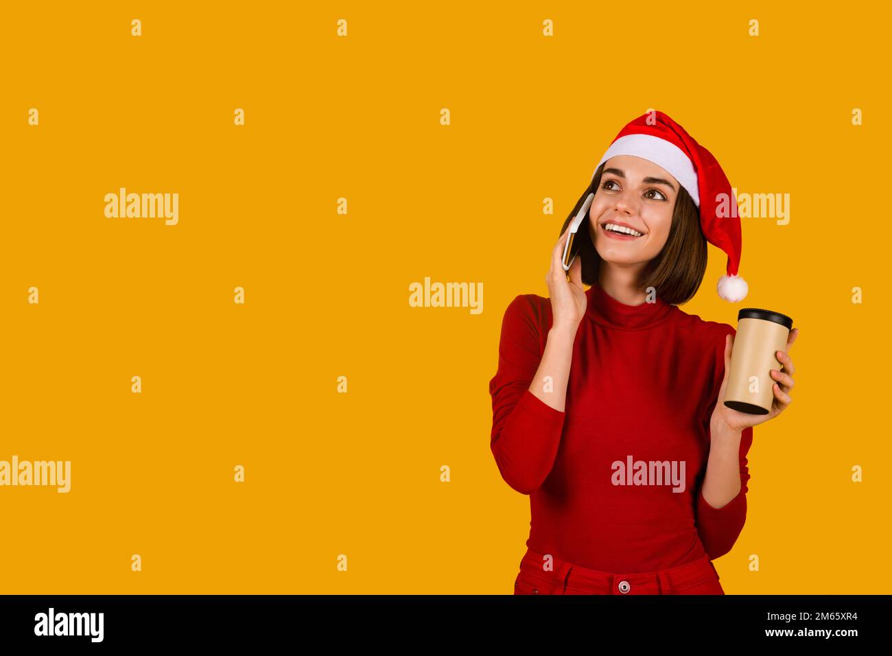 Eine reizende junge Frau mit Weihnachtsmann-Hut, die telefoniert Stockfoto