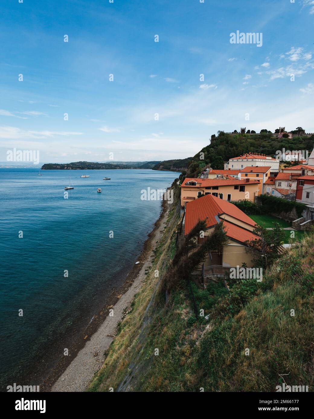 Ein vertikales Bild von Häusern auf einer Klippe in der Nähe des Meeres mit einem blauen Himmel im Hintergrund Stockfoto