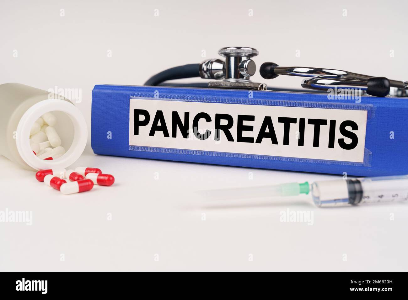 Medizinisches Konzept. Auf einer weißen Oberfläche sind Pillen, eine Spritze, ein Stethoskop und eine Mappe mit der Inschrift - Pankreatitis Stockfoto