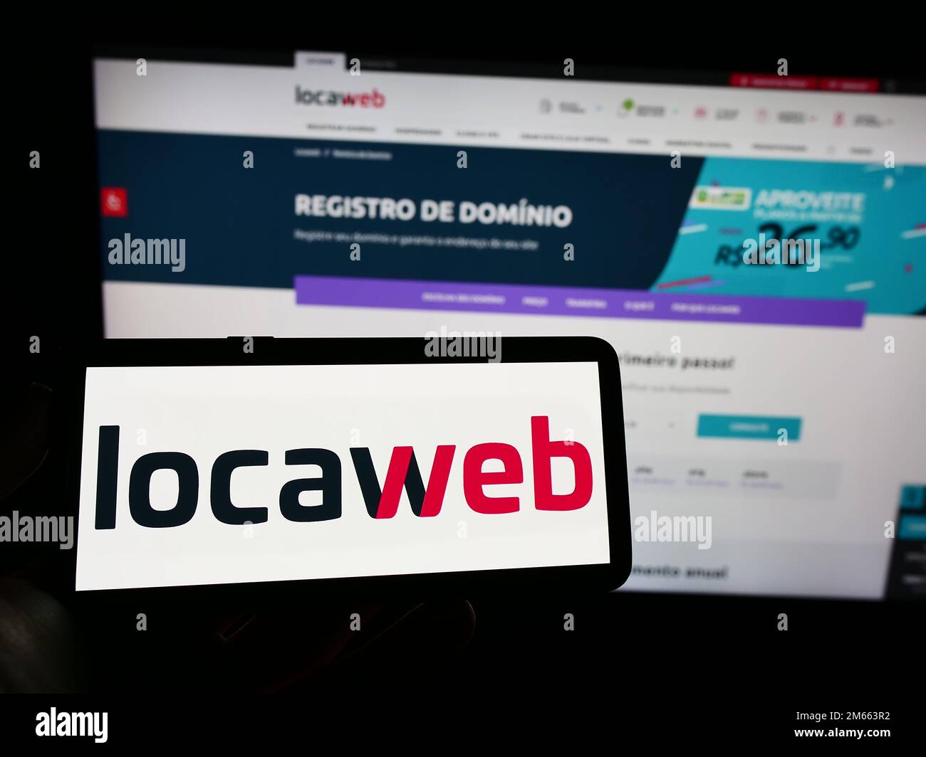 Person, die ein Mobiltelefon mit dem Logo des brasilianischen Webhosting-Unternehmens Locaweb auf dem Bildschirm vor der Unternehmenswebseite hält. Konzentrieren Sie sich auf das Display des Telefons. Stockfoto