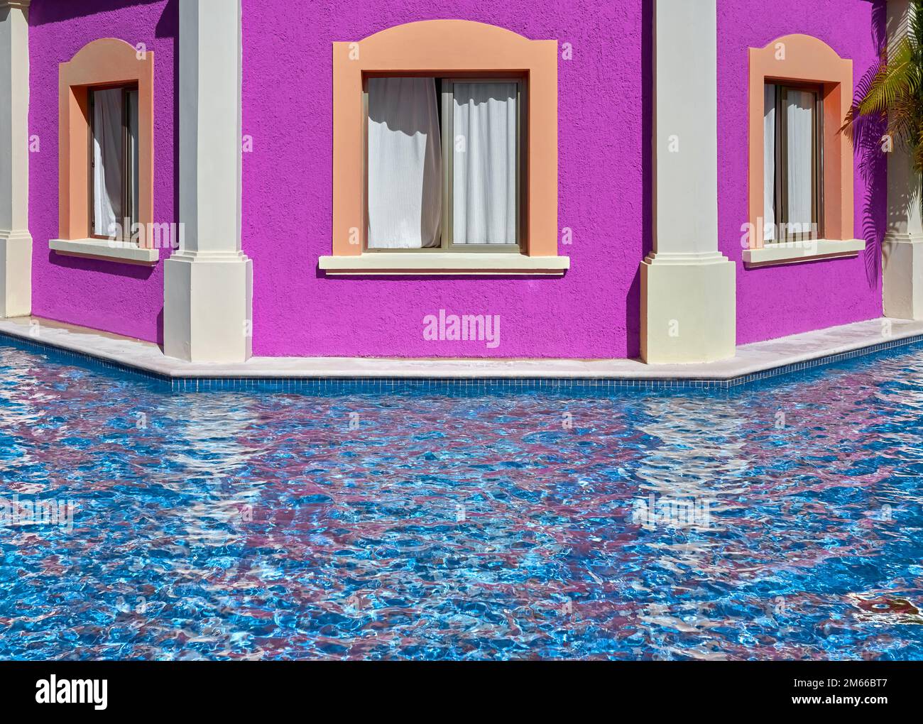 Rosafarbene Fassade mit Fenstern am Pool. Stockfoto