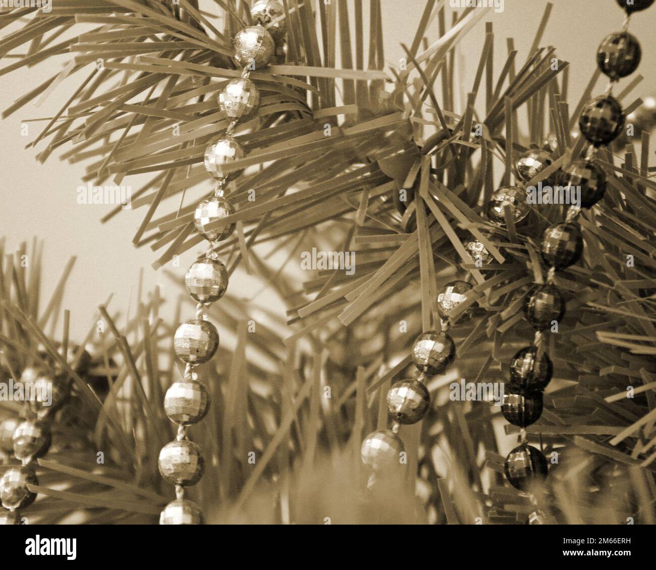 Perlenstränge über den Zweigen eines künstlichen Baumes im Sepia-Ton Stockfoto