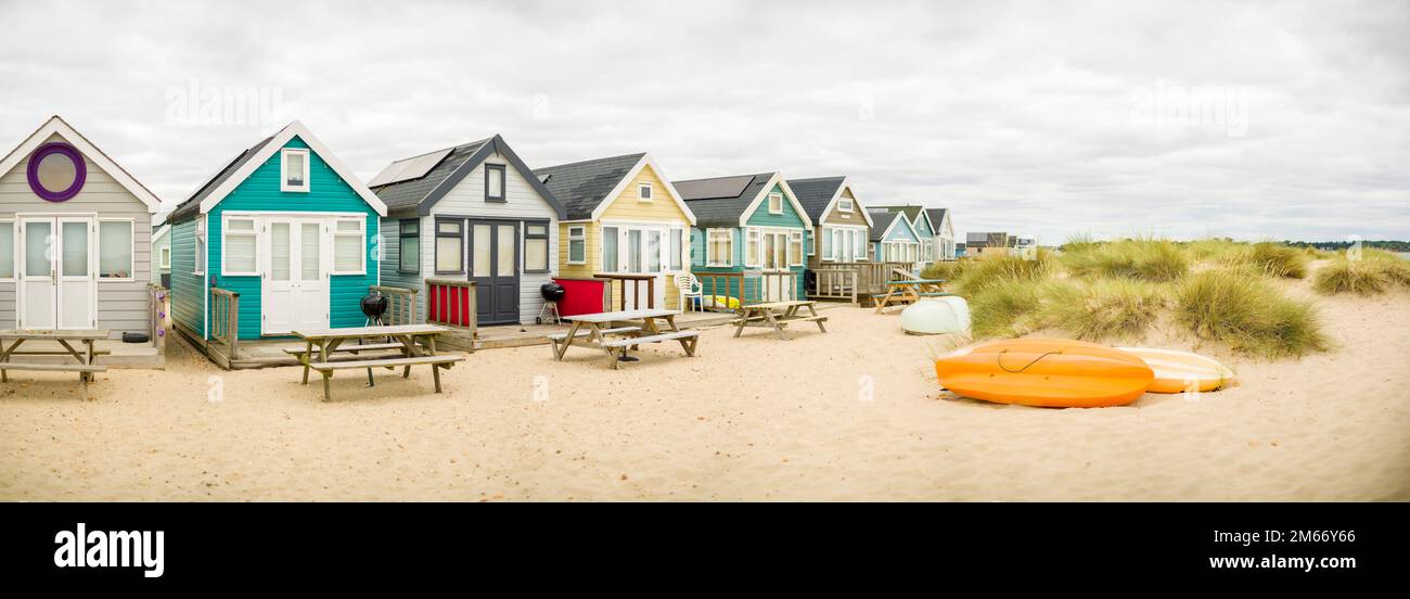 Panoramaszene mit einer Reihe farbenfroher Strandhütten inmitten von Sanddünen. Hengistbury Head, Dorset, Großbritannien Stockfoto