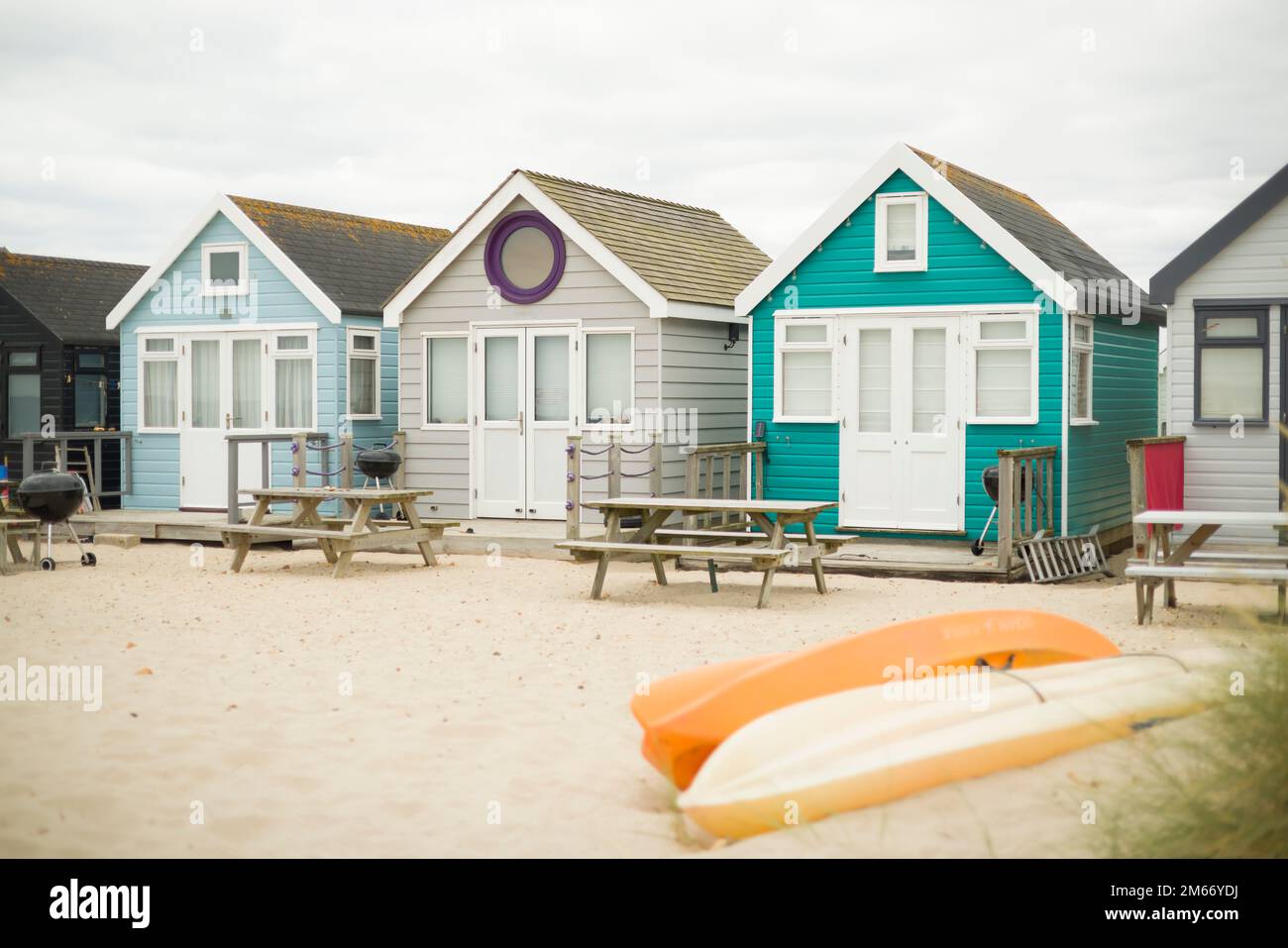 Farbenfroh bemalte Holzhütten an einem Sandstrand am Meer. Hengistbury Head, Dorest, Großbritannien Stockfoto