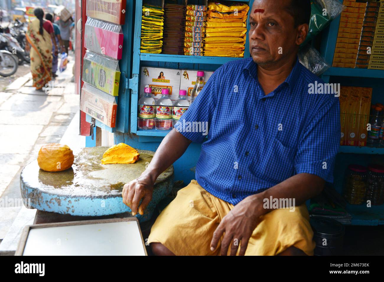 Ein Händler, der Öle, Parfüms und Sandelholzpaste in seinem Geschäft in Madurai, Tamil Nadu, Indien verkauft. Stockfoto