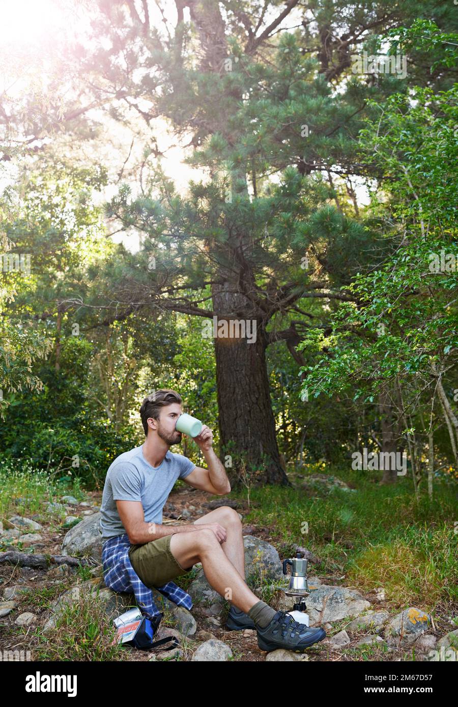 Pause im Wald. Ein junger Mann, der Kaffee trinkt, während er wandert. Stockfoto