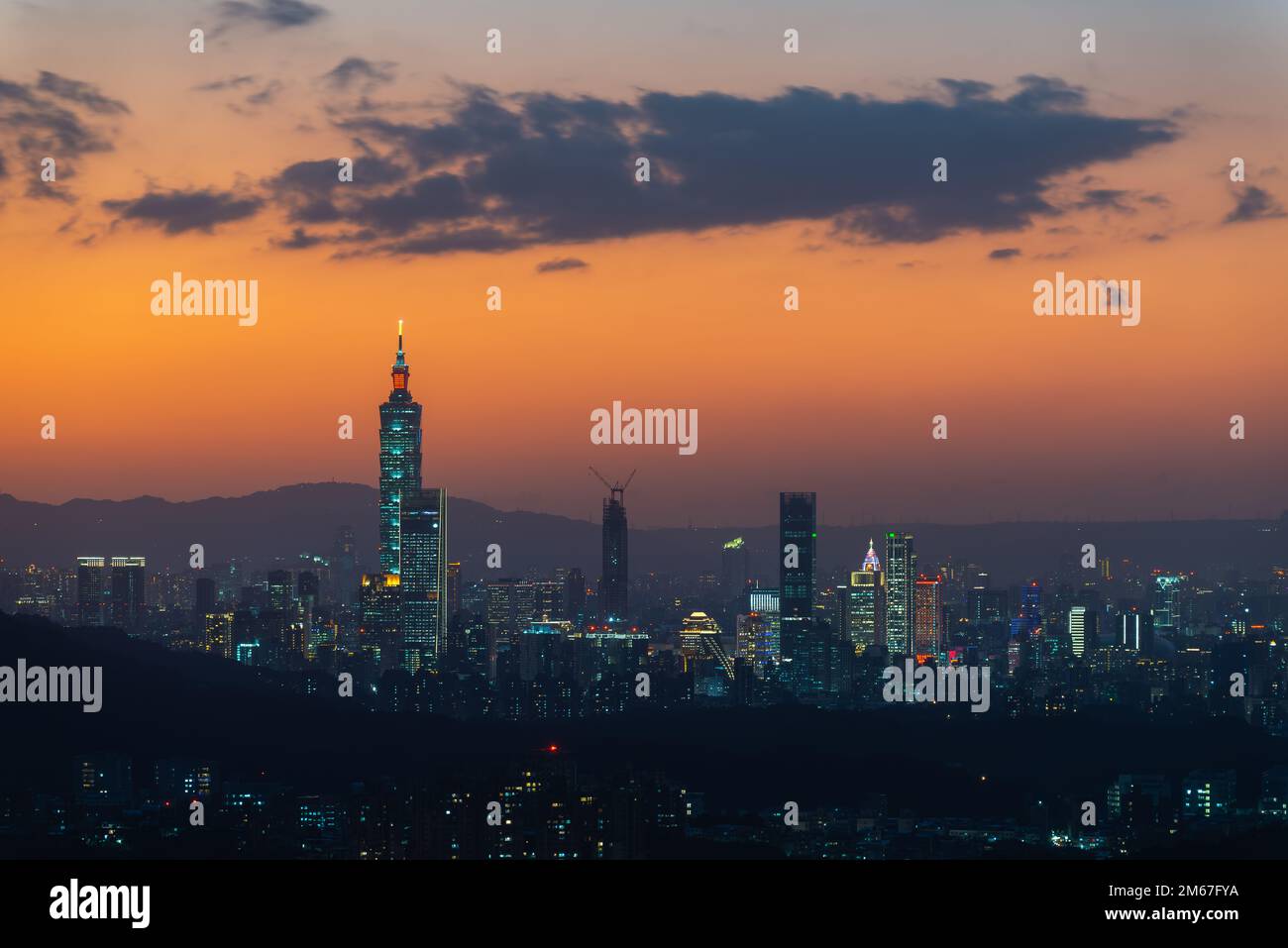 Ein pulsierendes Stadtbild mit einem orangefarbenen Nachthimmel. Die Aussicht auf die Stadt bei Nacht, umgeben von Bergen, ist trüb und traumhaft. Taipeh, Taiwan Stockfoto