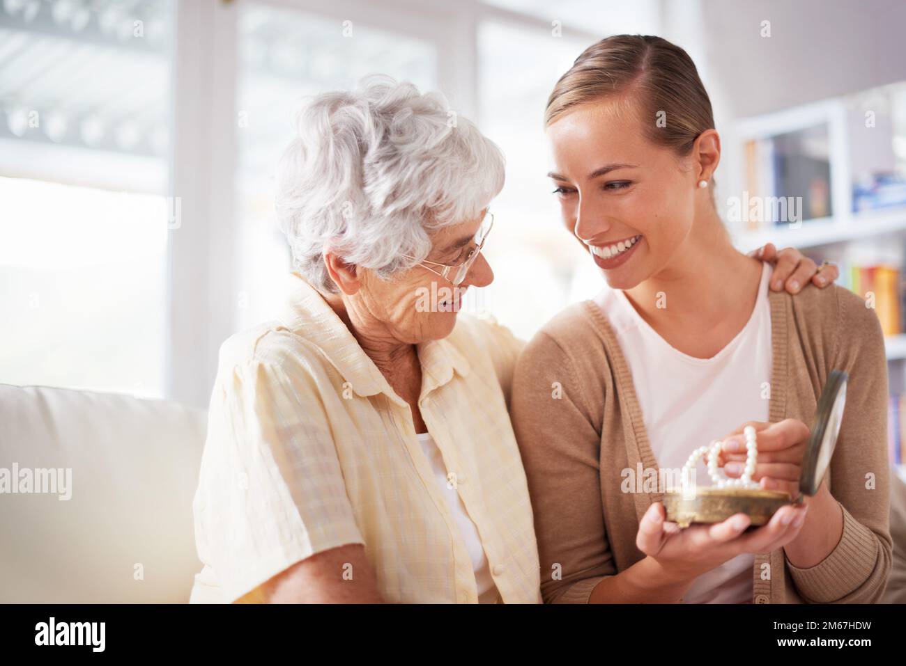 Dies ist ihr Familienerbstück. Eine ältere Frau gibt ihrer Tochter eine Perlenkette. Stockfoto