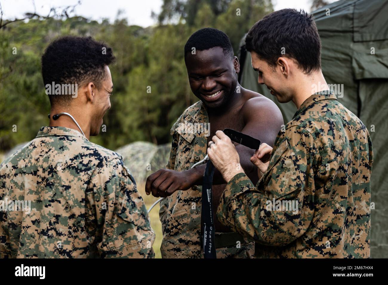 USA Navy Petty Officer 2. Klasse Joseph Nichols, Right, ein Sanitäter des Krankenhauses mit Combat Logistics Regiment 37, 3. Marine Logistics Group, demonstriert, wie man eine Blutdruckmanschette an der Marine Corps CPL anlegt. Christopher Dieujuste, Middle, ein Munitionstechniker bei der Munitionsfirma, 3. Sustainment Group (Experimental), 3. MLG, Während einer Marinekorps-Bereitschaftsbewertung an einem Munitionslieferpunkt im zentralen Ausbildungsgebiet, Okinawa, Japan, am 12. April 2022. Ein MCCRE ist eine formale Methode, die vom befehlshabenden General verwendet wird, um eine Einheit hinsichtlich ihrer Fähigkeit zur Ausführung ihrer Missi zu bewerten Stockfoto