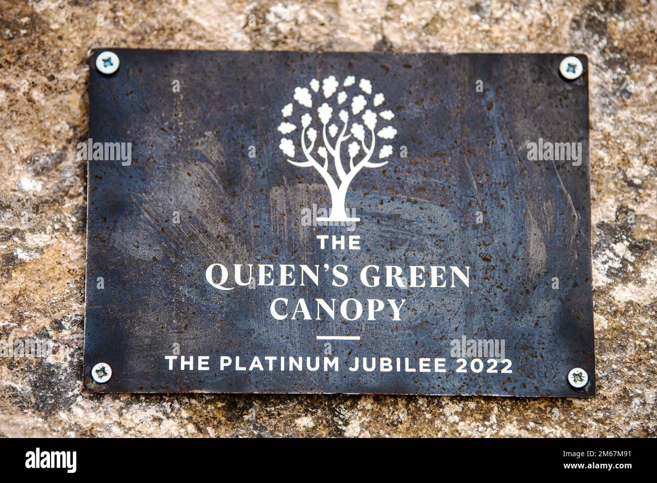 Eine Gedenktafel zum Gedenken an die Veranstaltung „The Queen's Green Canopy“ liegt auf einem Stein auf der RAF Croughton, England, am 13. April 2022. Die Veranstaltung feierte das Platinum Jubilee der Königin, das 70. Jahr ihrer Herrschaft. Während der Veranstaltung wurden Bäume gepflanzt, um ein Vermächtnis zu Ehren der Führung der Königin über die Nation zu schaffen. Stockfoto