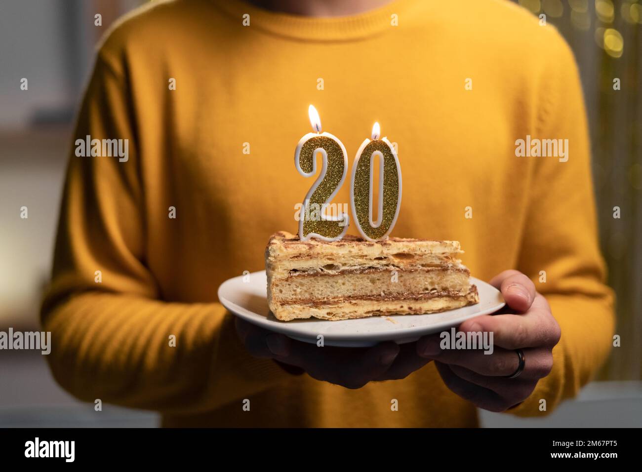 Kuchen mit der Nummer 20 brennenden Kerzen in Männerhänden. Zum 20. Geburtstag Stockfoto