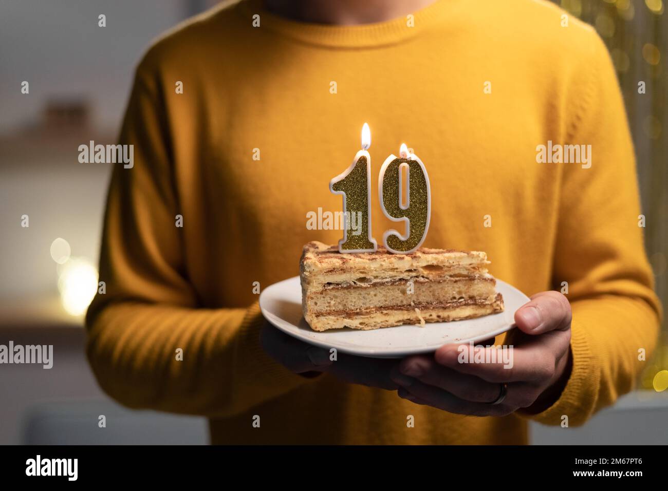 Kuchen mit der Nummer 19 brennenden Kerzen in Männerhänden. Zum 19. Geburtstag Stockfoto
