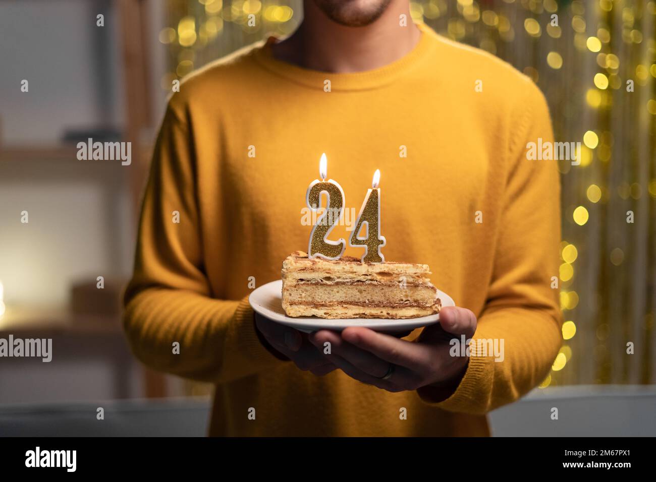 Kuchen mit der Nummer 24 brennenden Kerzen in Männerhänden. Zum 24. Geburtstag Stockfoto