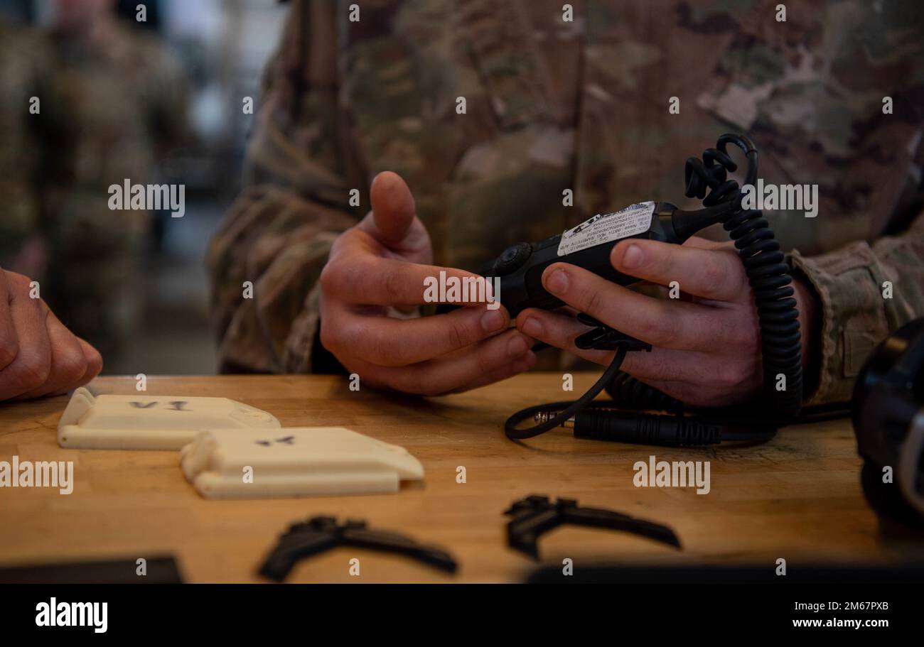 USA Air Force Tech Sgt. Aaron Barnes, 86. Maintenance Squadron Aircraft Metals Technology Uncommissioned Officer, verantwortlich für die Reparatur von Headsets und Kommunikationsgeräten am Luftwaffenstützpunkt Ramstein, Deutschland, am 13. April 2022, erläutert, wie der 3D-Druck eingesetzt wird. Brigg. General Josh Olson, 86. Kommandant des Luftwaffenflügels und Kommandochef Sergeant Charmaine Kelley besuchten die Metalltechnologie-Abteilung, um mehr über ihre Fähigkeiten zu erfahren. Stockfoto