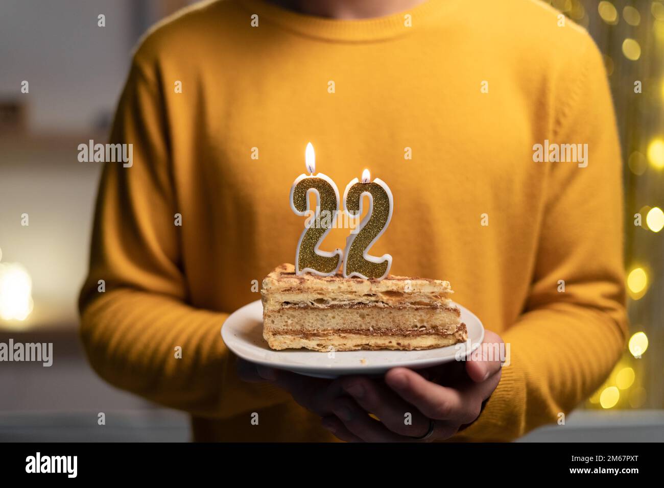 Kuchen mit der Nummer 22 brennenden Kerzen in Männerhänden. Zum 22. Geburtstag Stockfoto