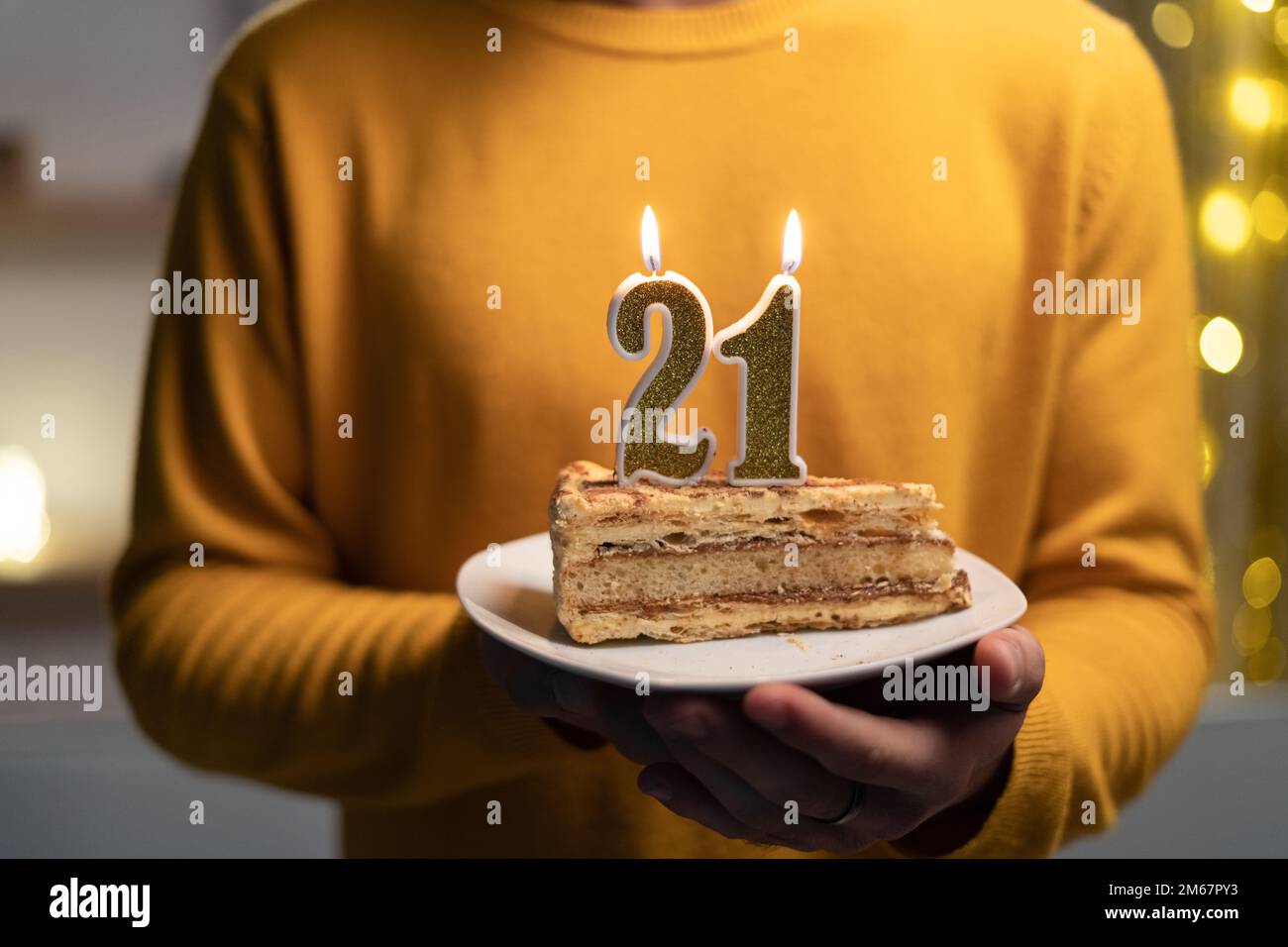 Kuchen mit der Nummer 21 brennenden Kerzen in Männerhänden. Zum 21. Geburtstag Stockfoto