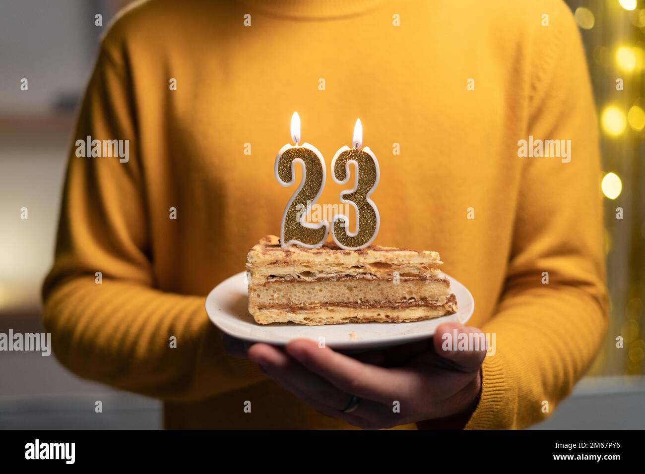 Kuchen mit der Nummer 23 brennenden Kerzen in Männerhänden. Zum 23. Geburtstag Stockfoto