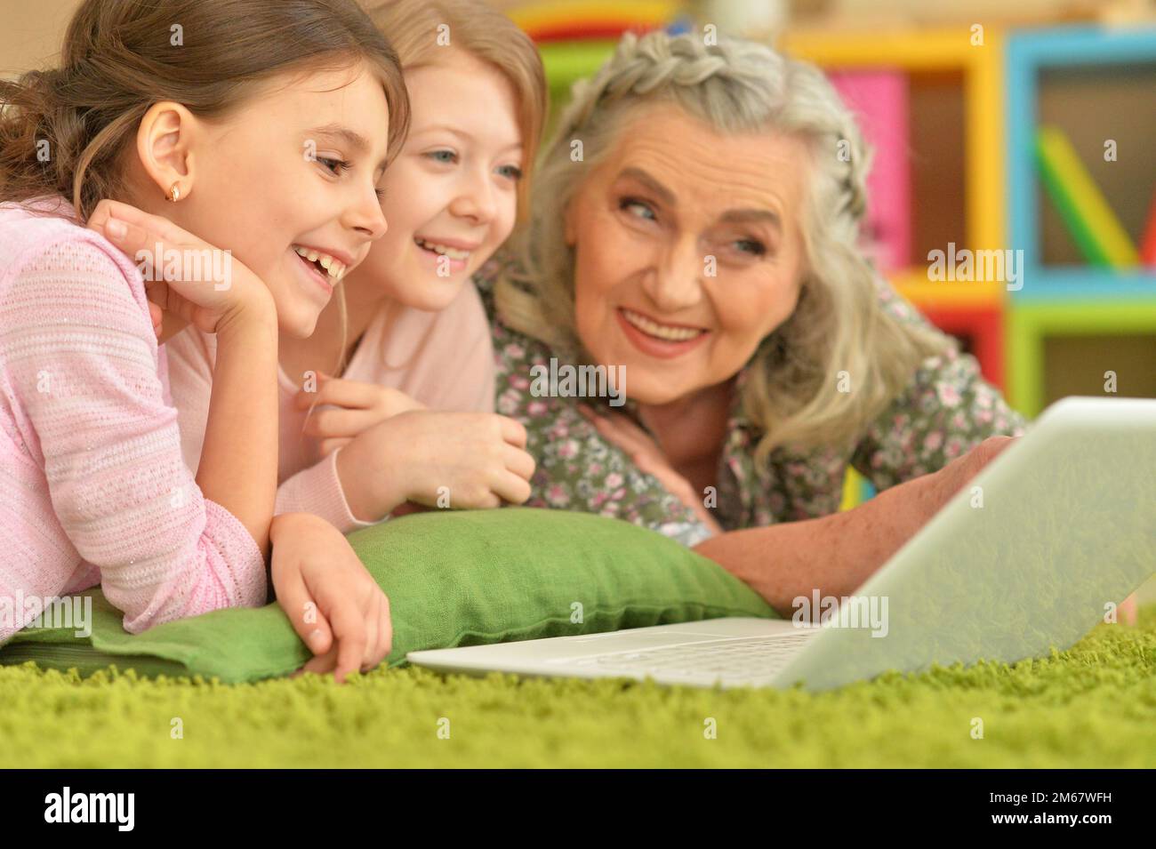 Seniorin mit Enkelinnen, die auf ein Notebook schauen Stockfoto