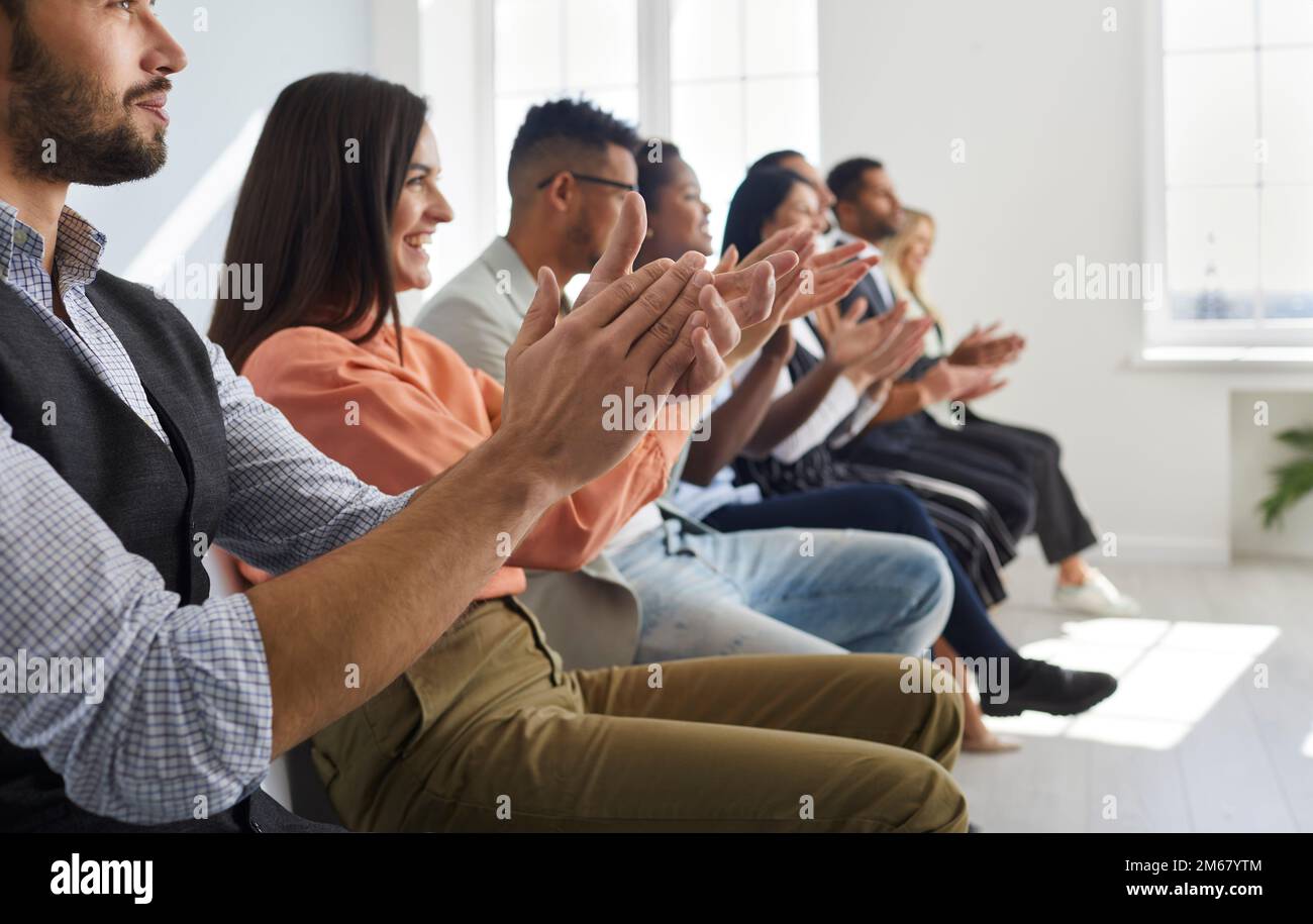 Eine Gruppe zufriedener Männer und Frauen in der Reihe applaudiert bei einer Geschäftskonferenz oder einem Teammeeting. Stockfoto
