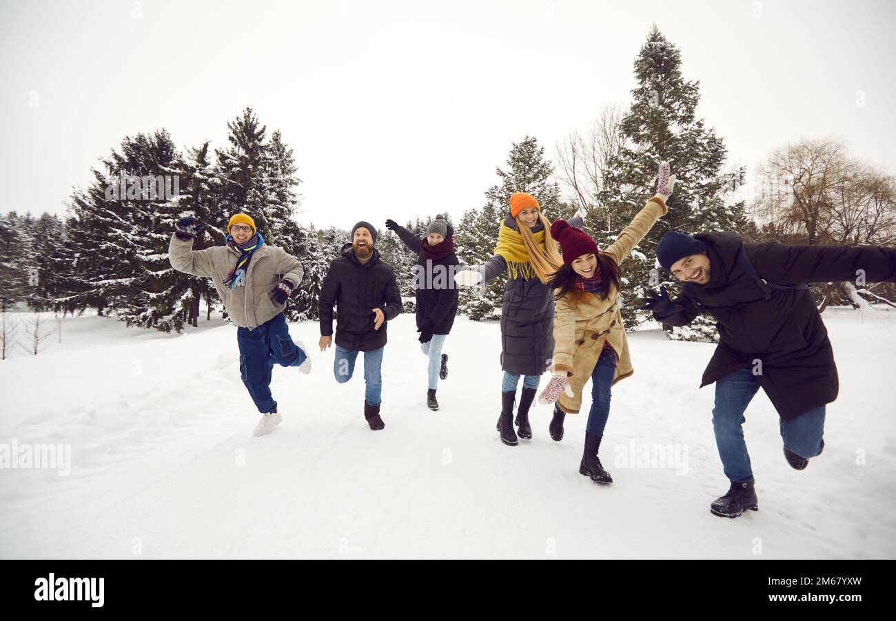 Eine Gruppe fröhlicher junger und sorgloser Freunde haben Spaß beim gemeinsamen Laufen im Schnee im Winterwald. Stockfoto