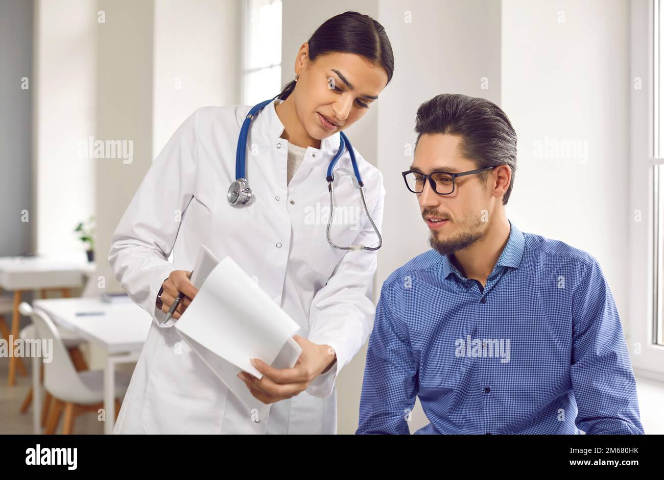 Weibliche Ärztin zeigt männlichen Patienten Testergebnisse in der Medizinischen Klinik Stockfoto