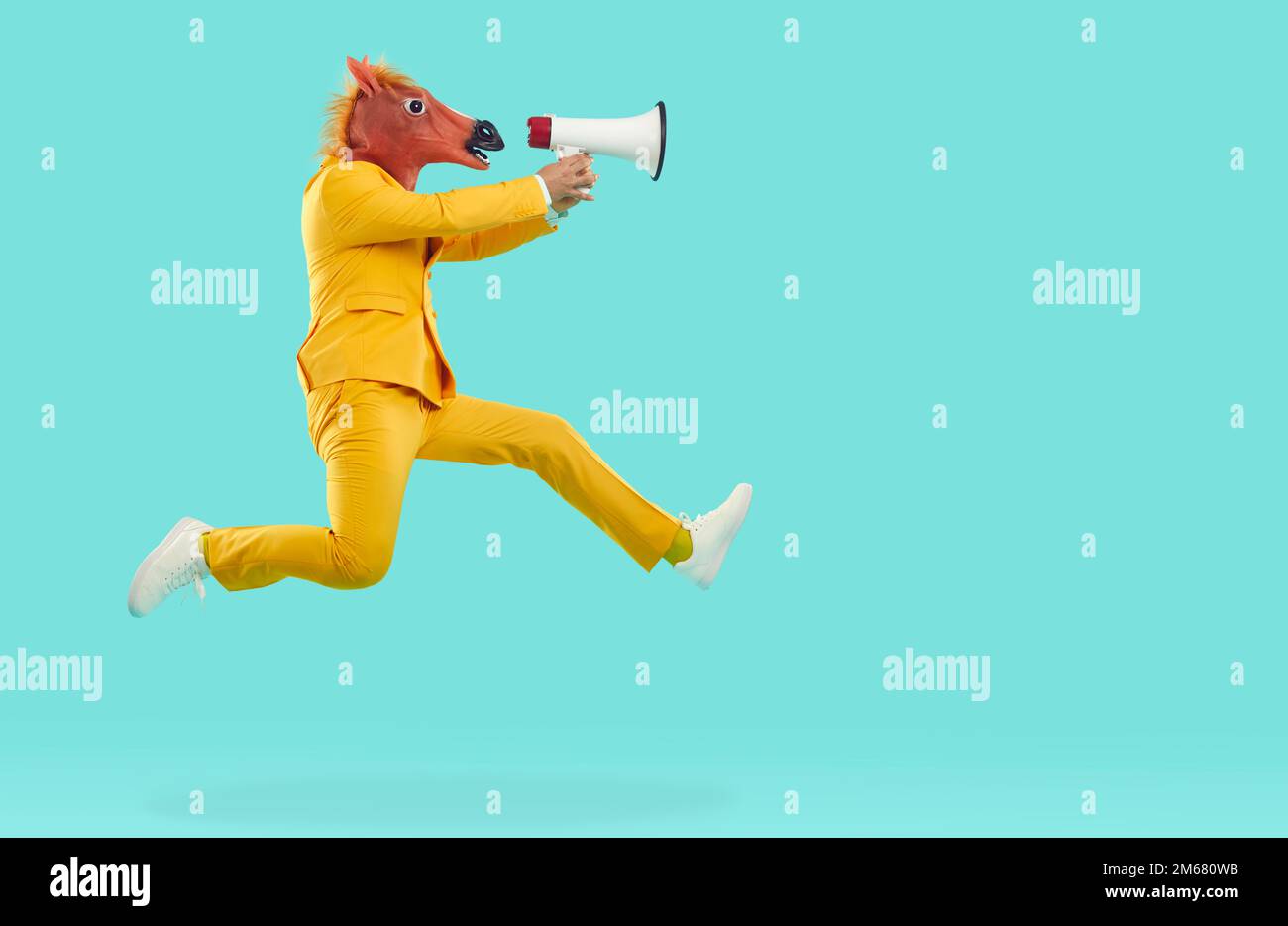 Mann mit Pferdekopfmaske springt und schreit in Megaphon Stockfoto