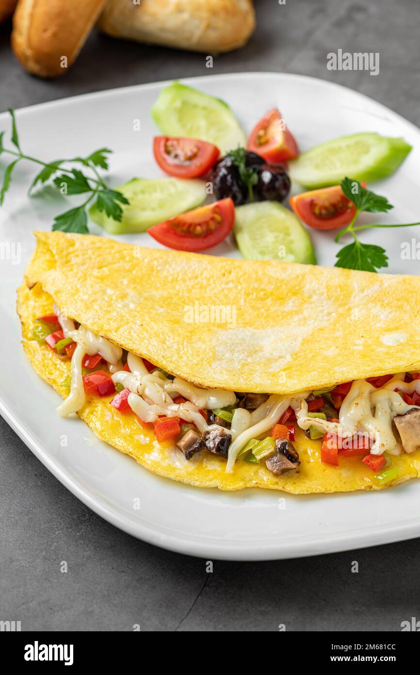 Omelett mit Käse, Pilzen und Gemüse auf einer weißen Porzellanplatte Stockfoto