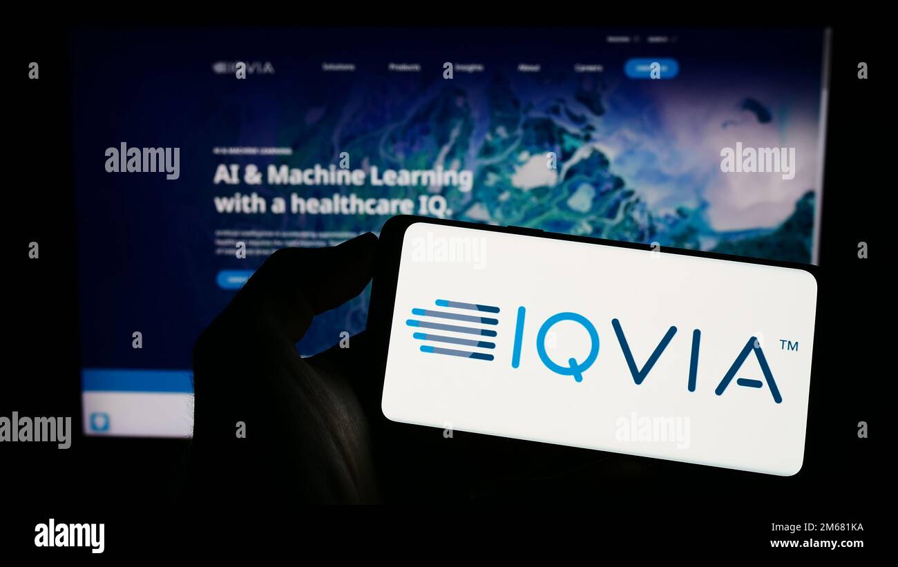 Person, die ein Handy mit dem Logo des amerikanischen Gesundheitstechnologieunternehmens IQVIA Holdings Inc. Auf dem Bildschirm vor der Webseite hält. Konzentrieren Sie sich auf das Display des Telefons. Stockfoto