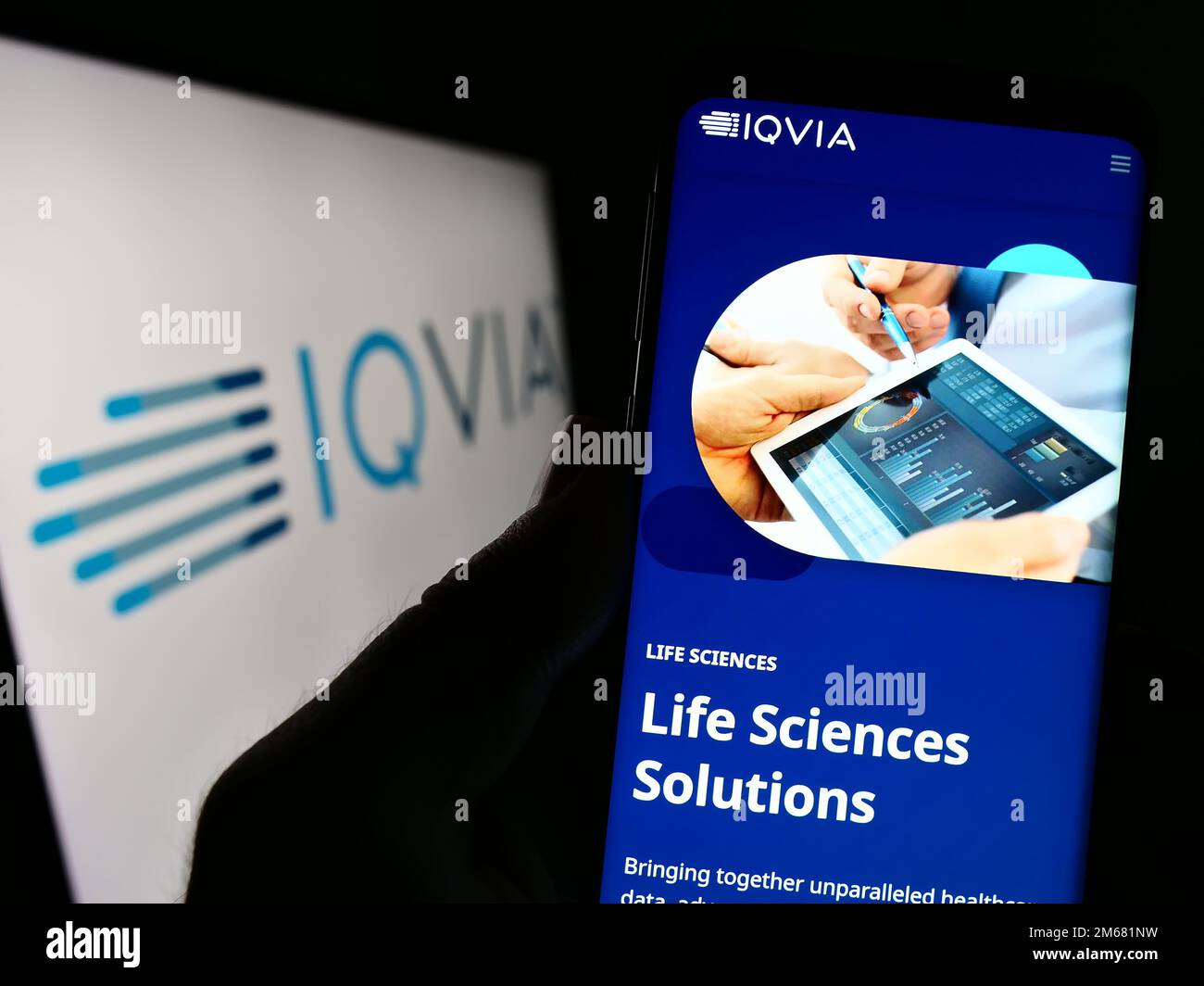Person, die ein Mobiltelefon mit der Website des US-amerikanischen Gesundheitstechnologieunternehmens IQVIA Holdings Inc. Auf dem Bildschirm mit Logo hält. Konzentrieren Sie sich auf die Mitte des Telefondisplays. Stockfoto