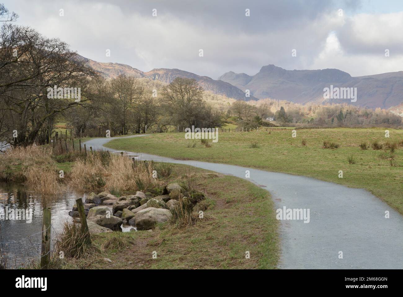 Am Ufer des Flusses Brathay in der Nähe von Elter Water im Lake District verläuft ein Fußweg. Mit den Langdale Hills im Hintergrund Stockfoto
