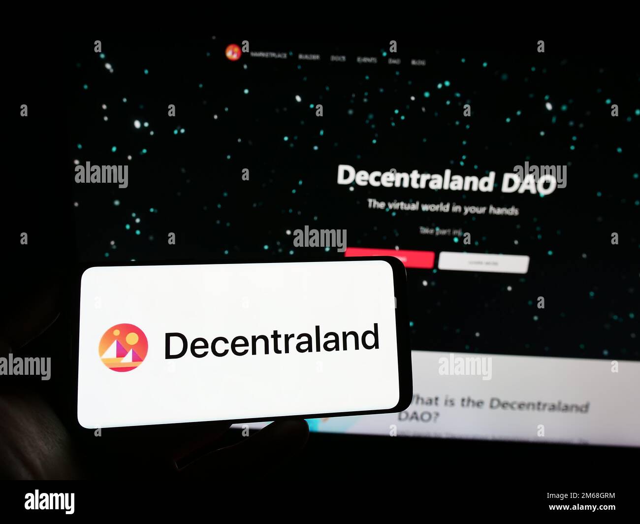 Person, die ein Smartphone mit dem Logo der Virtual-World-Plattform Deentraland auf dem Bildschirm vor der Website hält. Konzentrieren Sie sich auf das Display des Telefons. Stockfoto