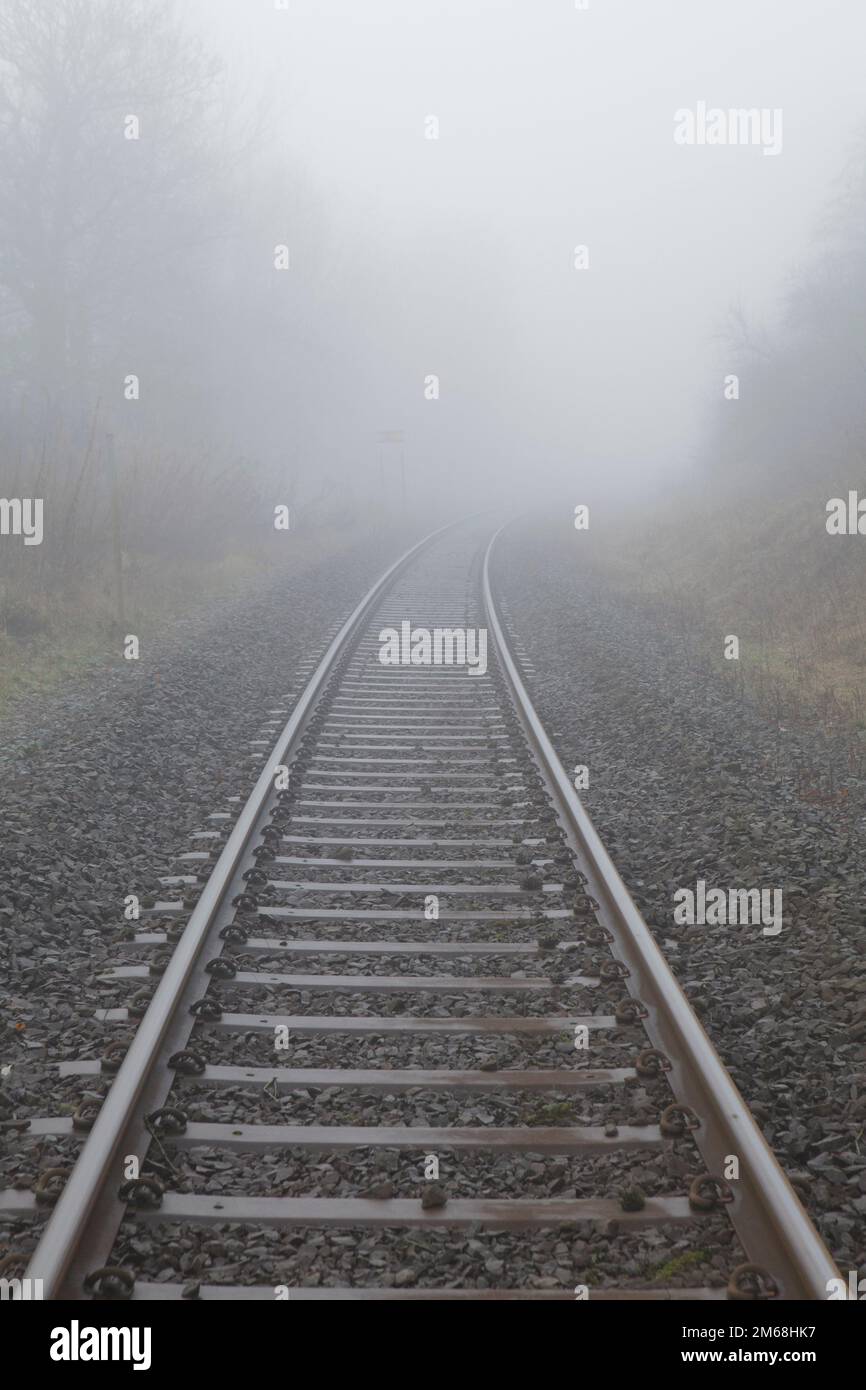 Eisenbahnschienen verschwinden im Nebel. Cumbria, England Stockfoto