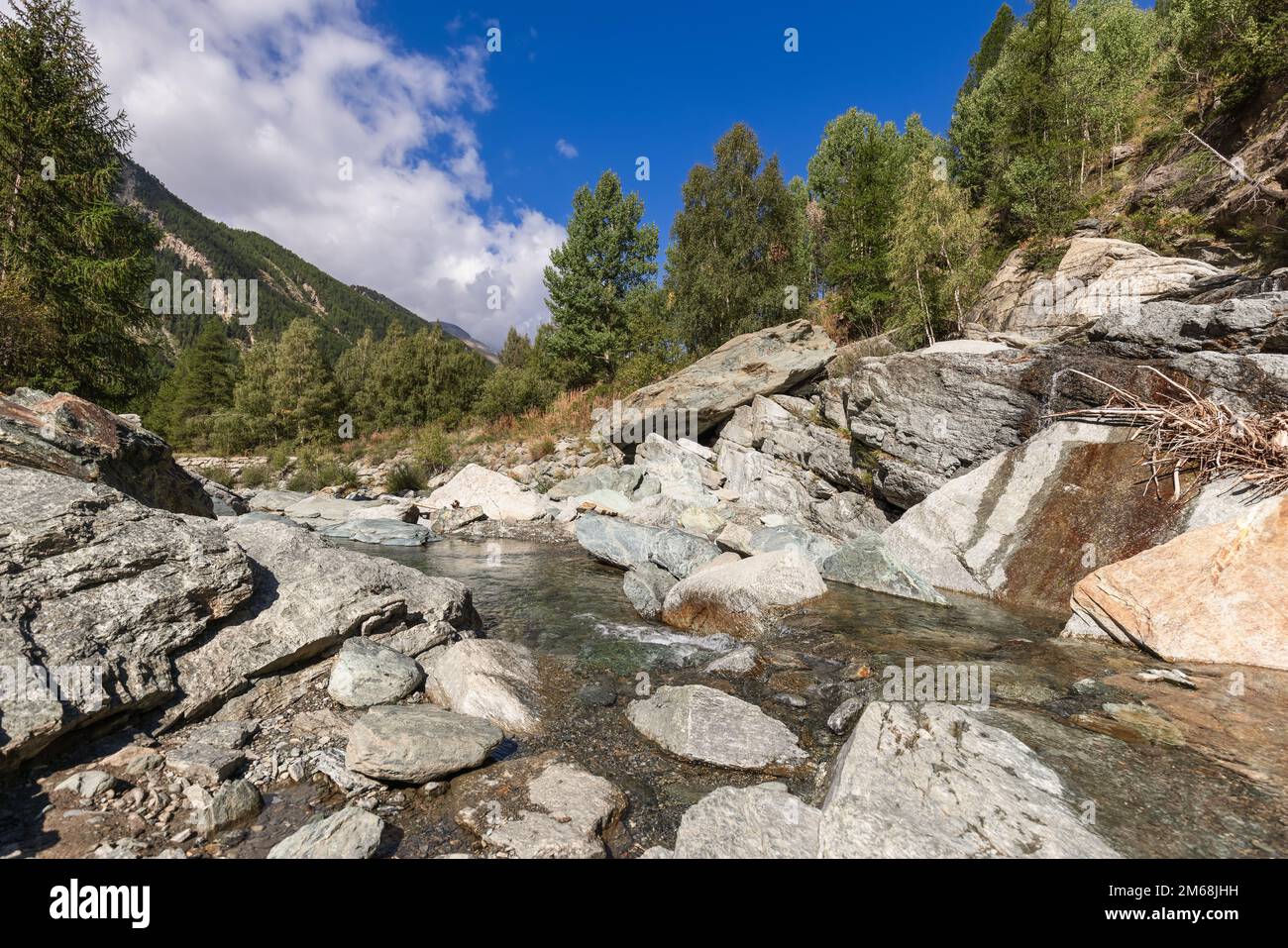 Torrente Grand Eyvia im Parco Nazionale del Gran Paradiso (Nationalpark Gran Paradiso) unter ultrablauem Himmel mit weißen Wolken Stockfoto