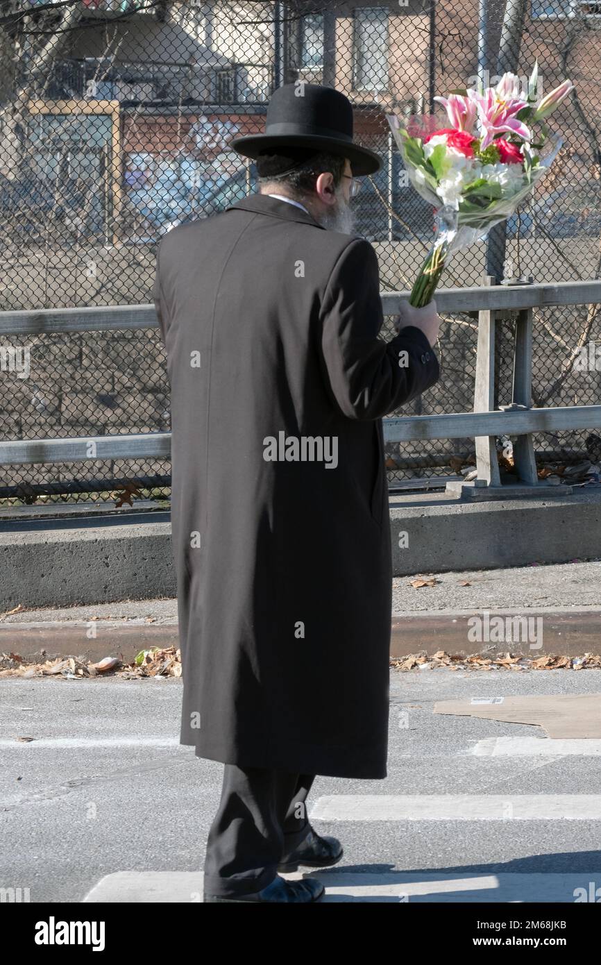 An einem Freitagnachmittag bereitet sich ein orthodoxer jüdischer Mann auf den Sabbat vor, indem er Blumen für sein Zuhause mitbringt. In Brooklyn, New York. Stockfoto