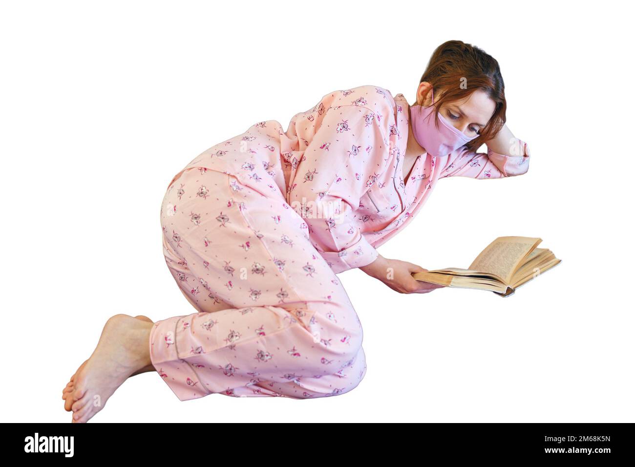 Eine Frau liegt auf einem Bett und liest ein Buch während der Krankheit mit der Influenza covid, isoliert auf weißem Hintergrund. Eine Frau in pinkfarbenen Pyjamas und einem Schutzanzug Stockfoto